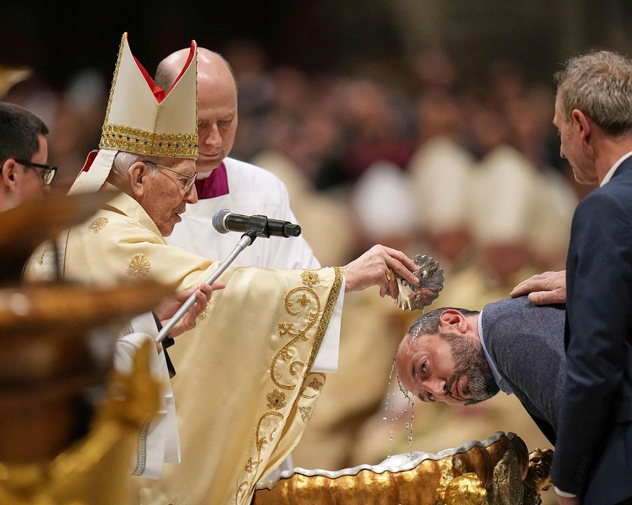 El cardenal Giovanni Battista Re bautiza a un hombre mientras dirige la Vigilia Pascual en la Basílica de San Pedro del Vaticano