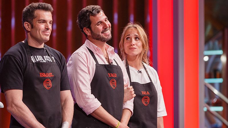 Tres concursantes con delantales negros y nombres bordados posan en el plat de MasterChef; se aprecian expresiones variadas y el fondo del set.